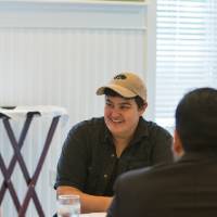 Faculty members talk and laugh at a table.